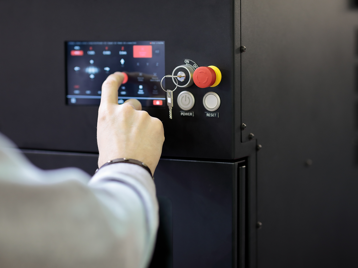 Operator using industrial touchscreen control panel with emergency stop